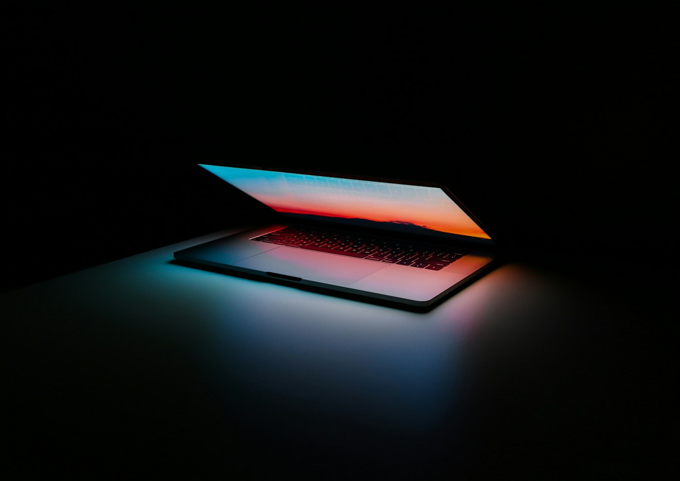 Notebook escuro com a tela acesa em degradê — landing page